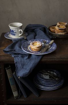 a table topped with plates and cups filled with pastries on top of a wooden table