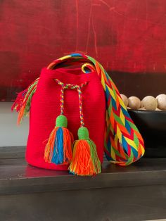 a red bag with colorful tassels sits on a shelf next to some rocks