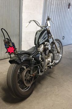 a black motorcycle parked in a garage next to a metal building with a red star on it