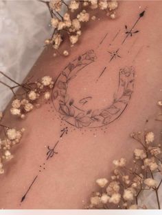 a tattoo on the back of a woman's stomach with flowers and arrows in it