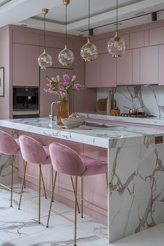 a kitchen with marble counter tops and pink chairs in front of an island that's surrounded by hanging lights