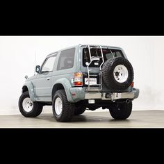 a grey four - door suv parked on top of a hard wood floor in a white room