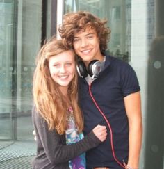 a young man and woman standing next to each other with headphones around their necks