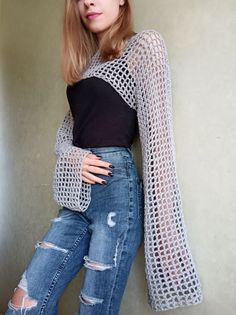 a woman in ripped jeans leaning against a wall