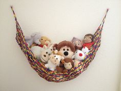 a hammock filled with stuffed animals hanging from the side on a white wall