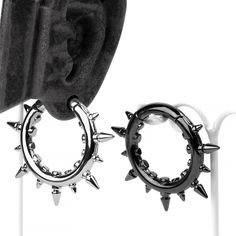 two pairs of hoop earrings with spikes attached to them, one is black and the other is silver