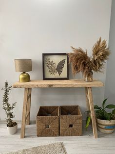 a wooden table with two baskets underneath it and a framed photograph on the wall next to it