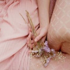 a close up of a person holding flowers in their hands and laying on the ground