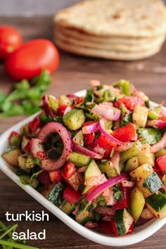 a salad with red onions, cucumbers and green peppers in a white bowl