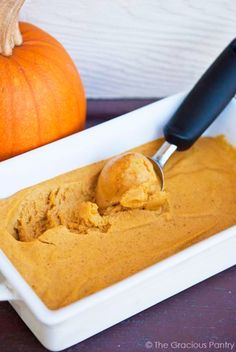 a scoop of pumpkin ice cream in a white bowl with a black spoon next to it