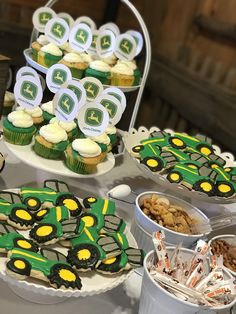 a table topped with cupcakes covered in green frosting and tractor themed decorations