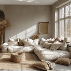 a living room filled with lots of furniture and pillows on top of a white floor