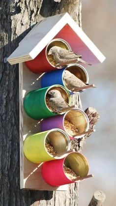 a bird house made out of tin cans on a tree trunk with birds in it