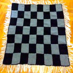 a black and gray checkered rug sitting on top of a wooden floor