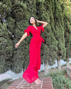 a woman in a red dress is posing for the camera with her hands on her head