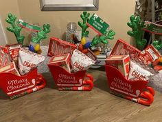 some christmas candy boxes are sitting on a table with cactuses and other holiday decorations