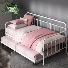 a white metal bed with pink pillows and blankets