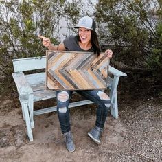 a woman sitting on a bench holding up a wooden sign with arrows painted on it