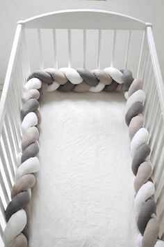 a white crib with a gray and white blanket on it's bottom half