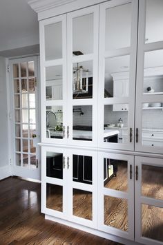 a kitchen with white cabinets and wood floors