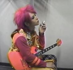 a woman with pink hair sitting on top of a chair