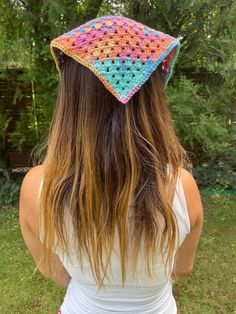 a woman with long hair wearing a crocheted hat on her head and back to the camera