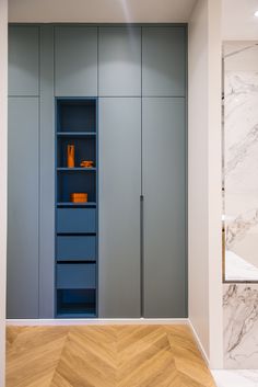 an empty room with blue shelves and white marbled walls, along with herringbone wood flooring