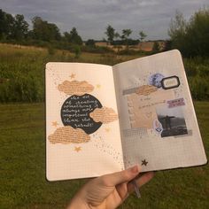 an open notebook with writing on it in someone's hand, near some grass