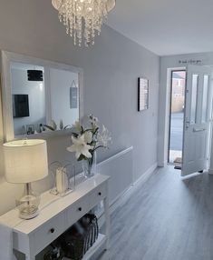 a living room with a white table and chandelier hanging from the ceiling next to a doorway