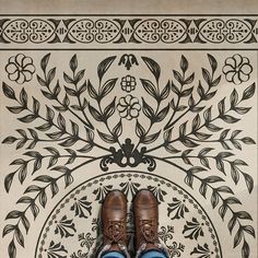 a pair of brown shoes sitting on top of a tiled floor next to a wall