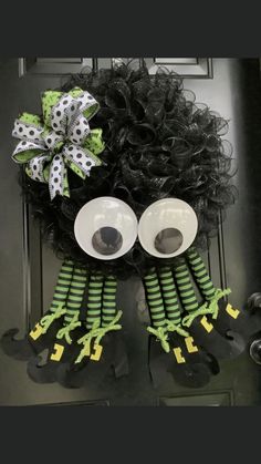 a wreath decorated with googly eyes and green hair is hanging on the front door