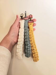 four crochet keychains in different colors being held by a person's hand