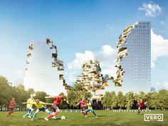 a group of people playing soccer on a field with buildings in the backgroud