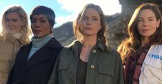 three women standing next to each other with mountains in the background