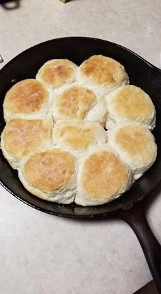 a cast iron skillet filled with biscuits on top of a counter next to a knife