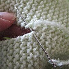 someone is stitching the end of a knitted sweater