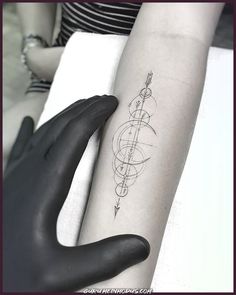 a woman's arm with an arrow and compass tattoo on the left inner forearm