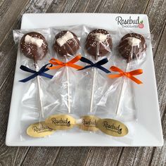 four chocolate lollipops wrapped in cellophane on a white plate