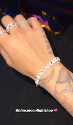 a person's hand with tattoos and bracelets on it