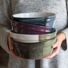 a woman holding several bowls in her hands