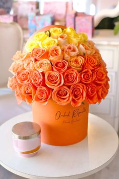 an orange hat box with roses in it sitting on a table next to a container