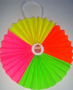 a colorful paper fan hanging on the wall with a cupcake in it's center