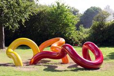 three large inflatable objects sitting on top of a lush green field next to trees