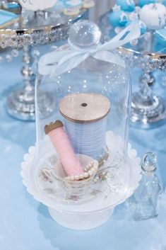 two spools of thread are under a glass clochet on a table