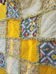 a yellow and white quilt with sunflowers on the edges is laying on a table