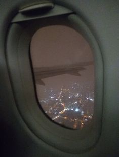 an airplane window looking out at the city lights