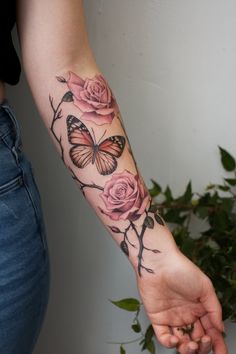 a woman's arm with pink roses and butterflies on it