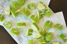 several pieces of green fruit are arranged on a piece of paper with toothpicks stuck in them