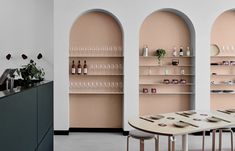 an empty dining room with pink walls and shelves filled with bottles, plates and bowls