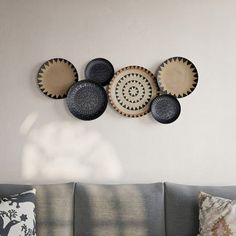 a living room with a gray couch and four decorative plates on the wall